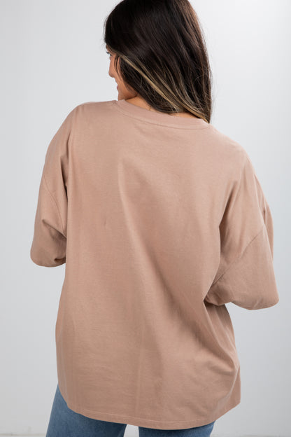 Woman wearing a beige oversized shirt against a white background