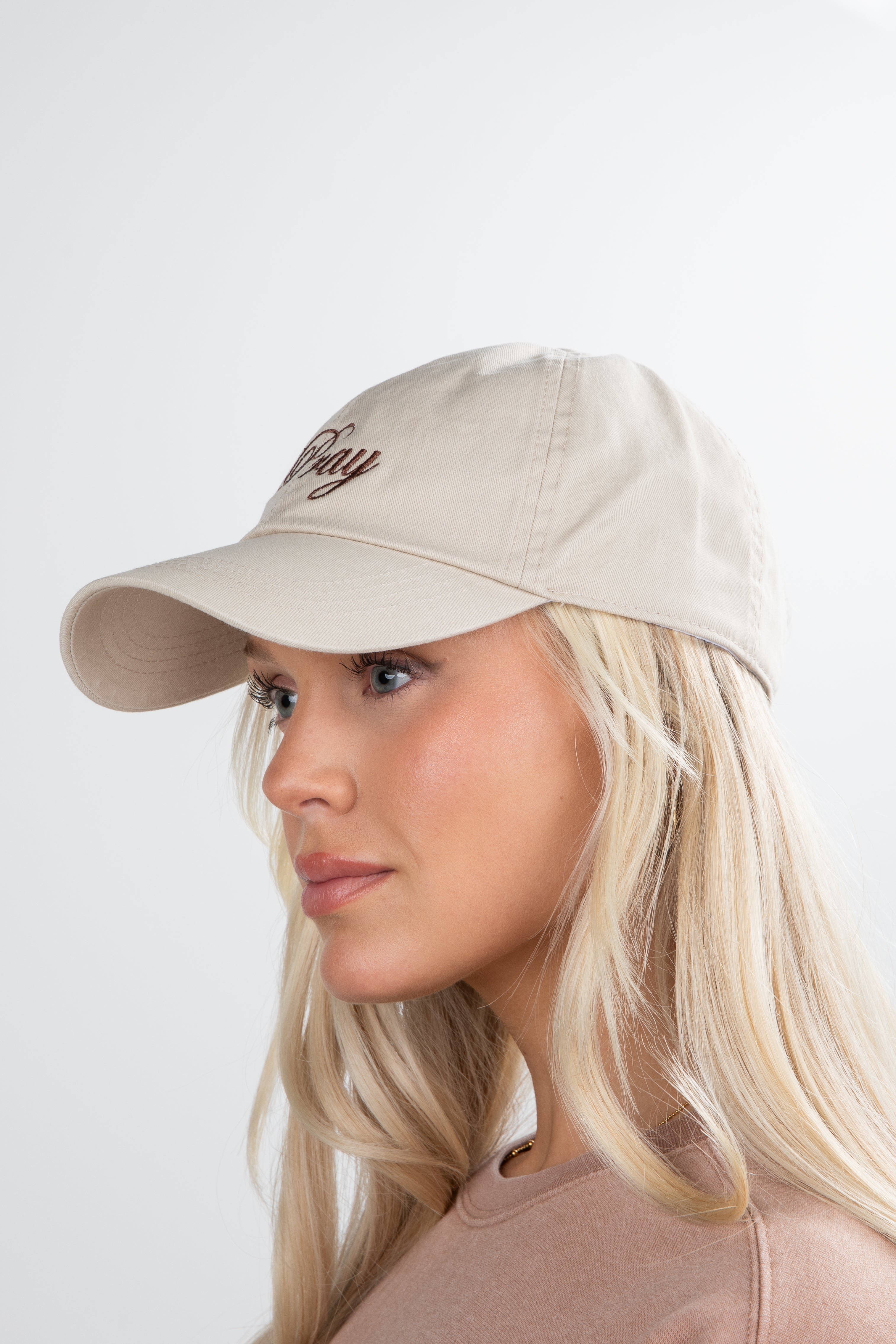 Woman wearing a beige cap with text on a white background