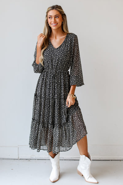 model wearing a black leaf print Midi Dress with white western booties