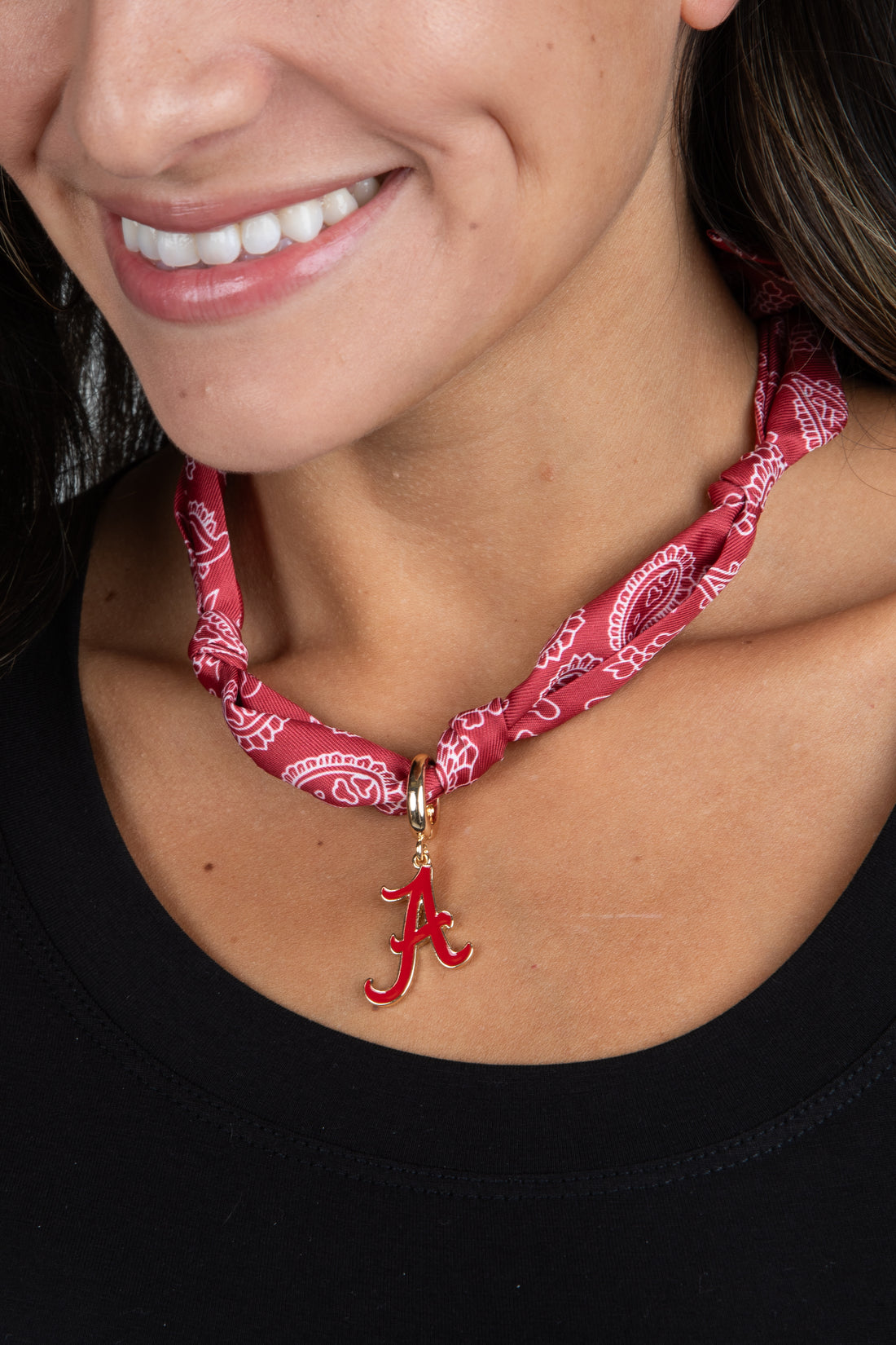 Person wearing a red bandana necklace with a letter &