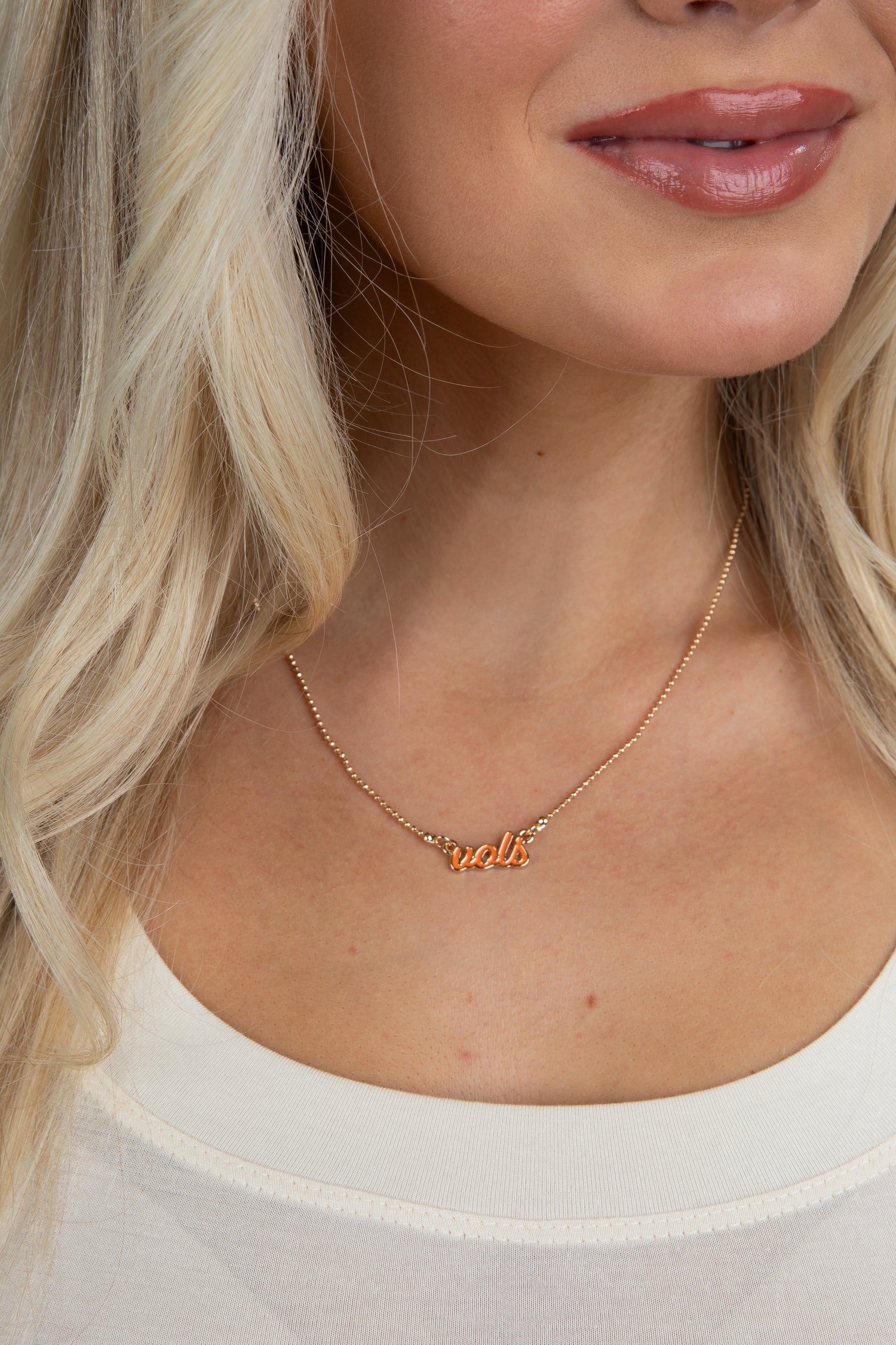 Close-up of a woman wearing a gold necklace with small charms.