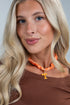 Woman wearing an orange necklace with a &