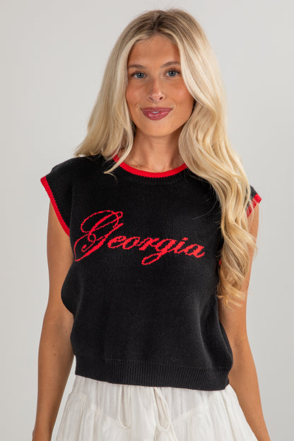 Woman wearing a black sleeveless top with red lettering on a plain background