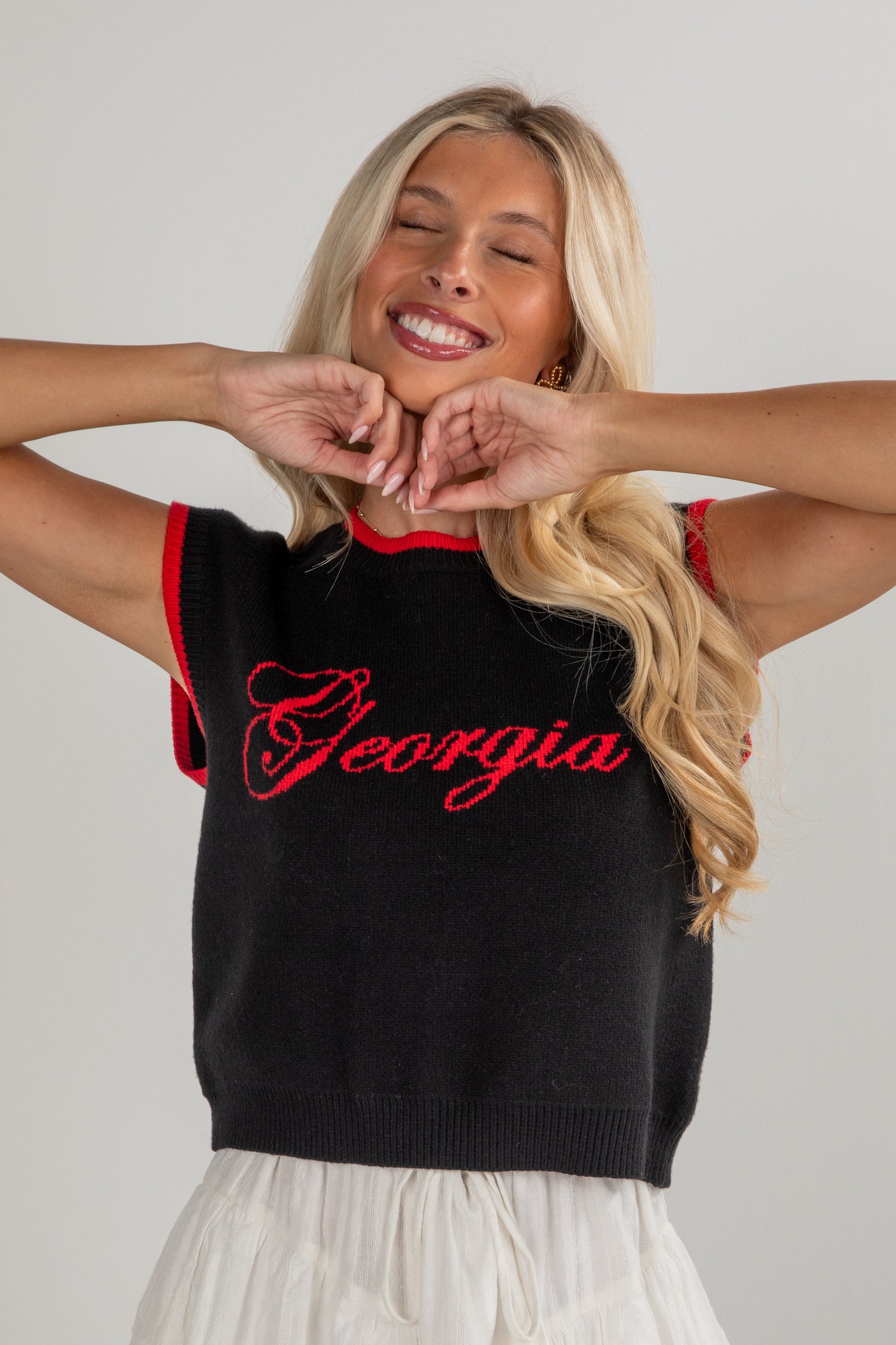 Woman wearing a black sleeveless sweater with &