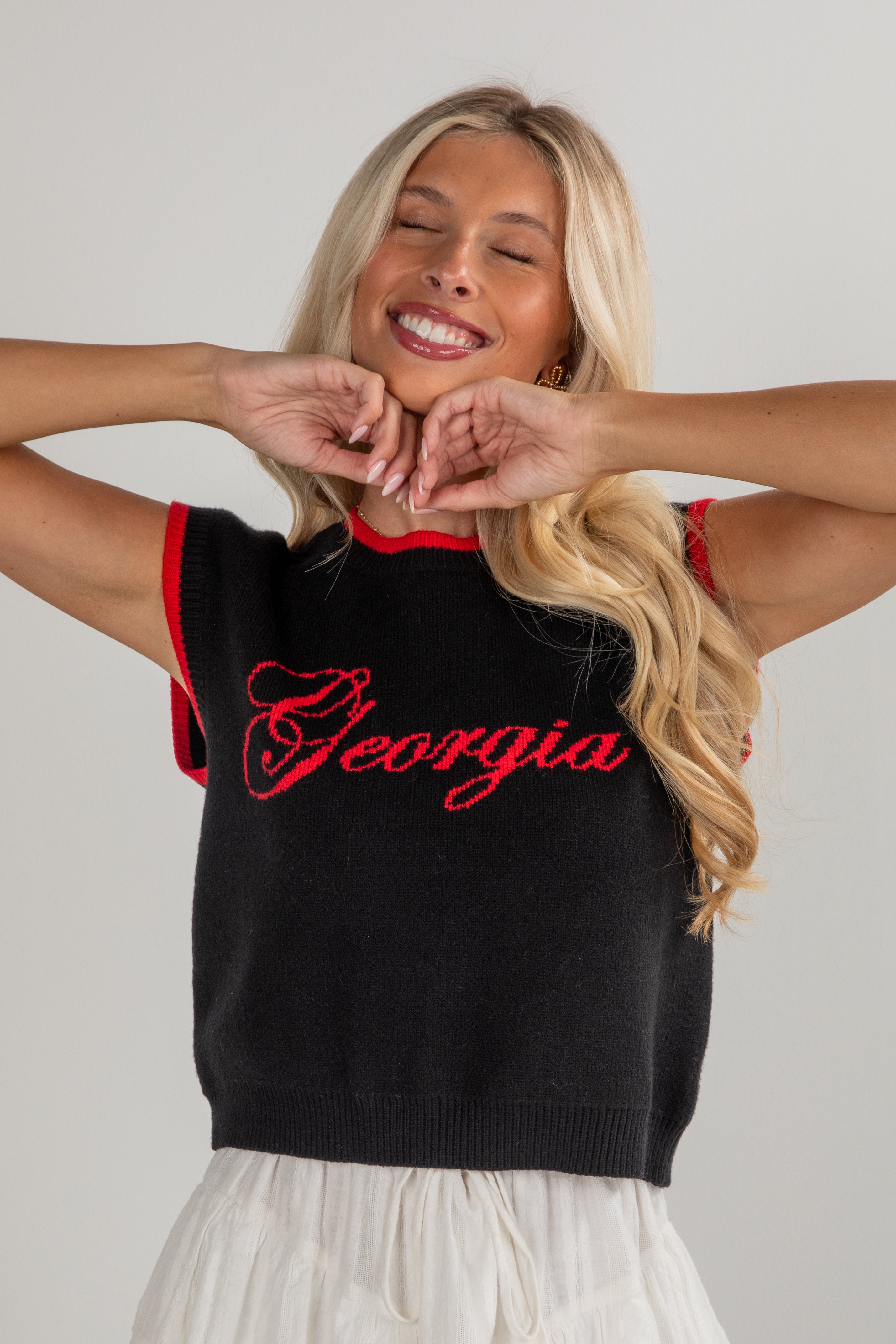 Woman wearing a black sleeveless sweater with &