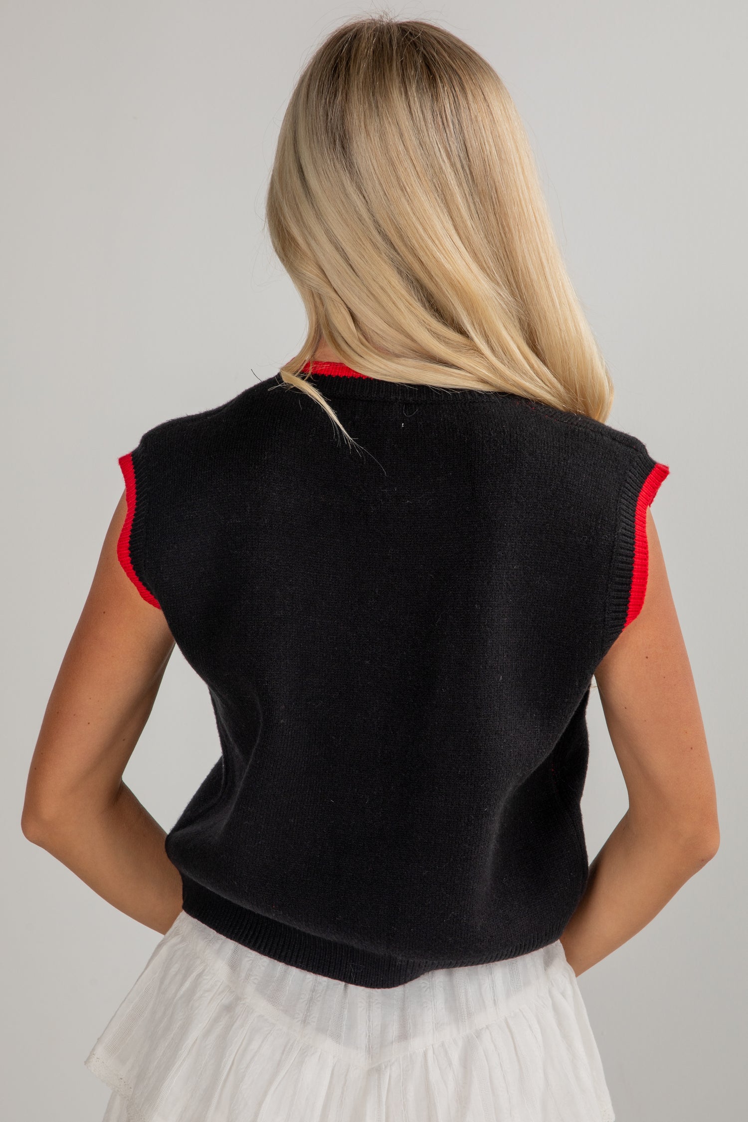 Woman wearing a black sleeveless top with red trim on a gray background