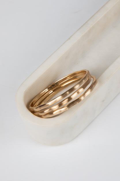Two gold rings on a white marble surface