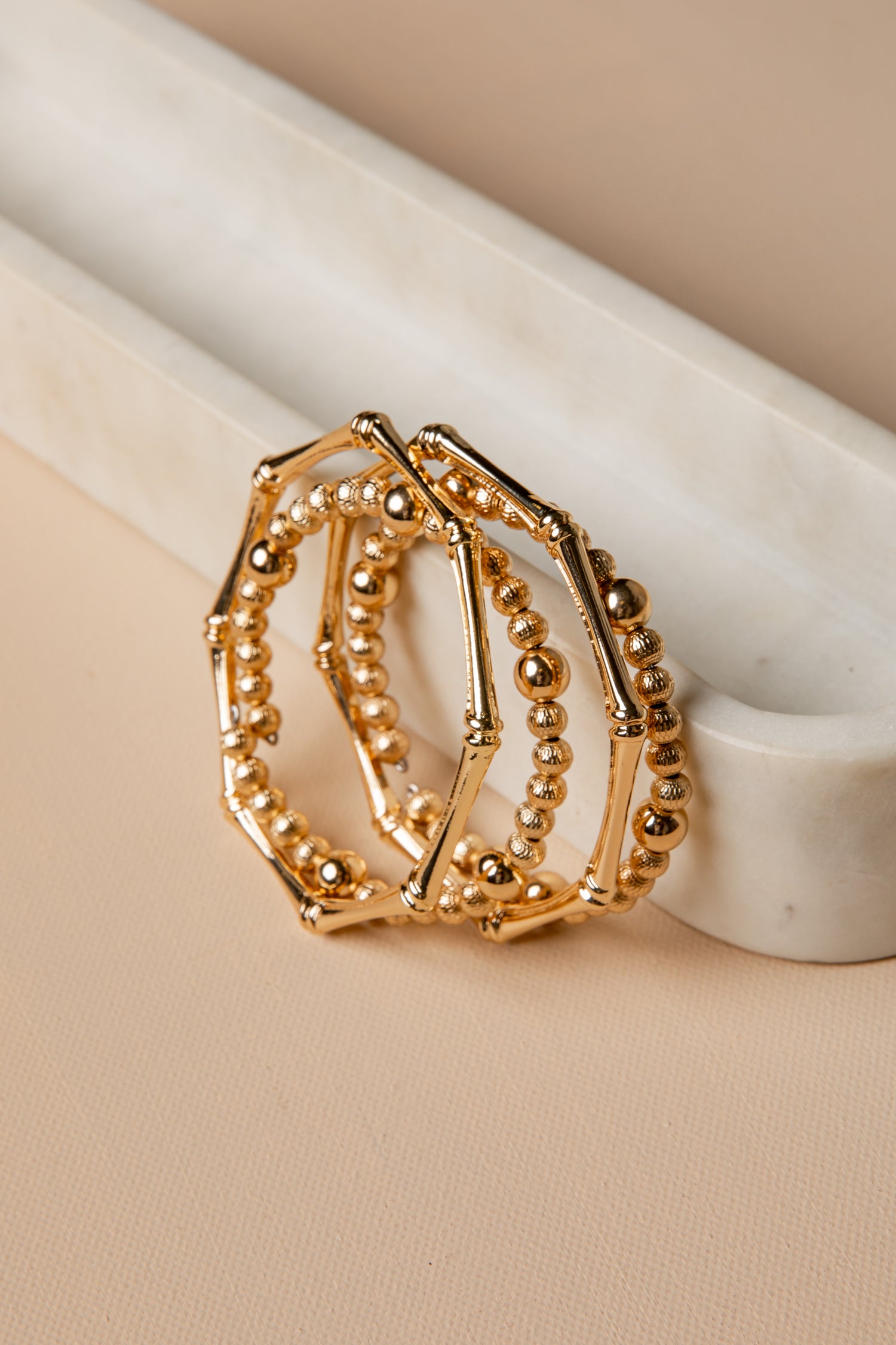 Gold ring with beaded design on a beige surface