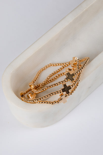 Gold necklace with cross pendants on a white dish