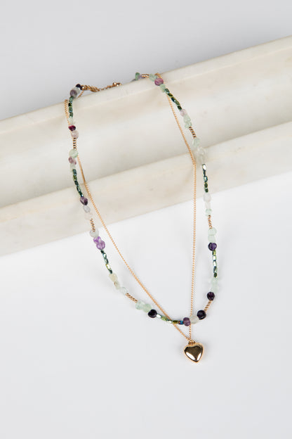 Multicolored beaded necklace with a heart pendant on a white surface