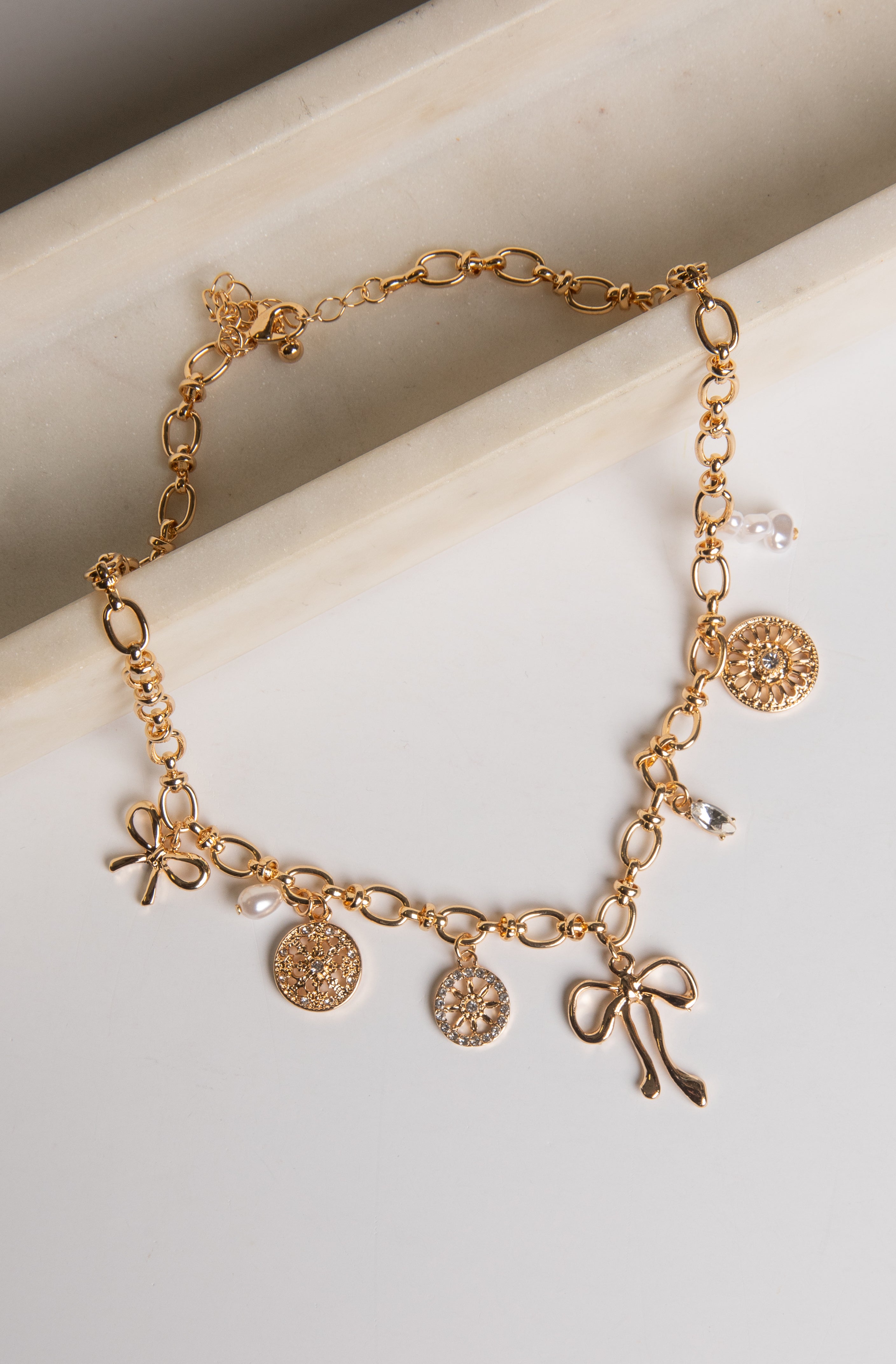 Gold bracelet with various charms on a light background