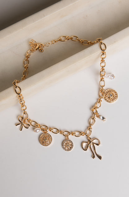 Gold bracelet with various charms on a light background