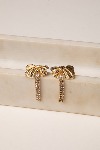 Gold earrings with tassel design on a beige surface