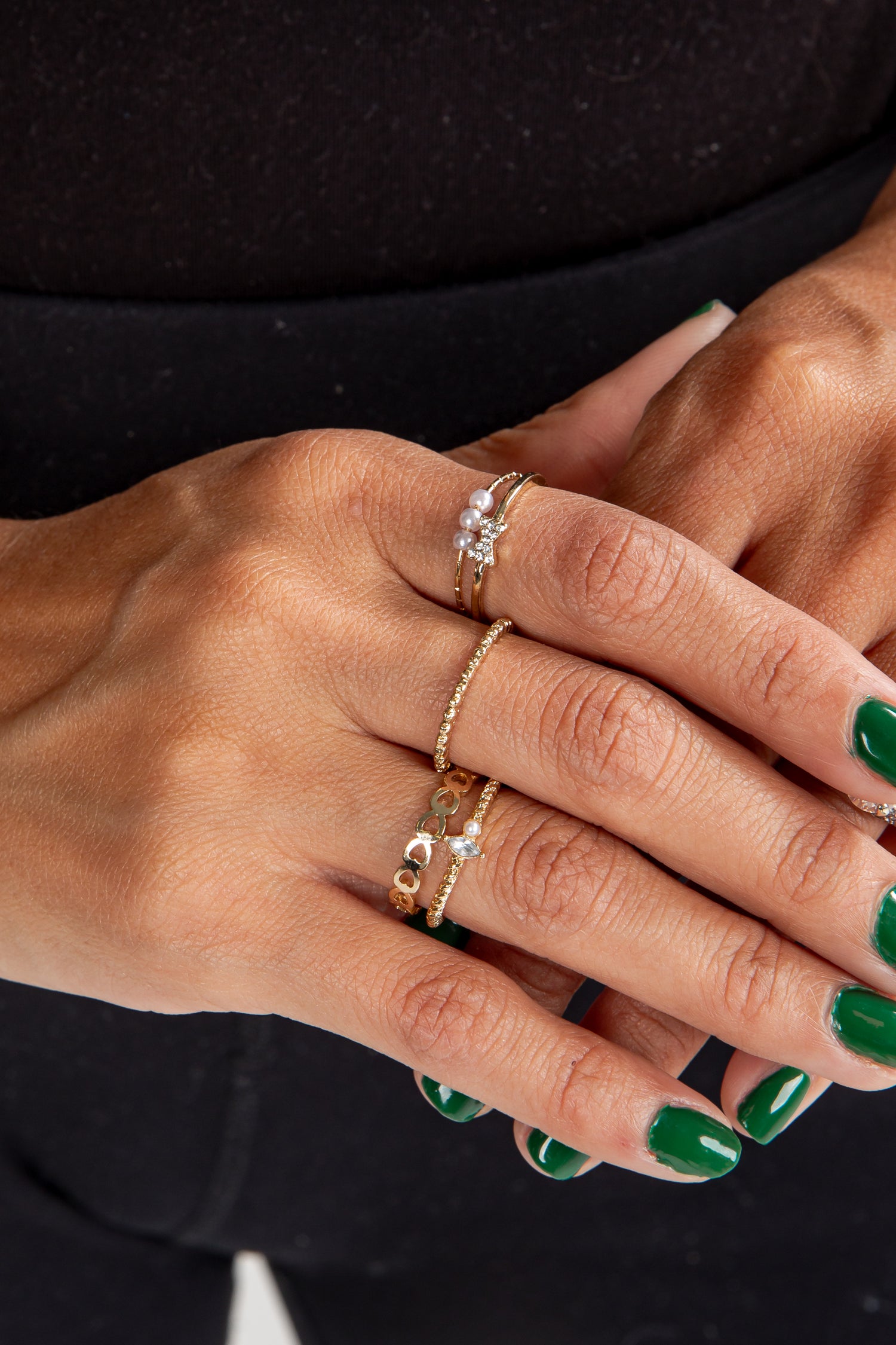 Close-up of a hand with multiple gold rings on a black background