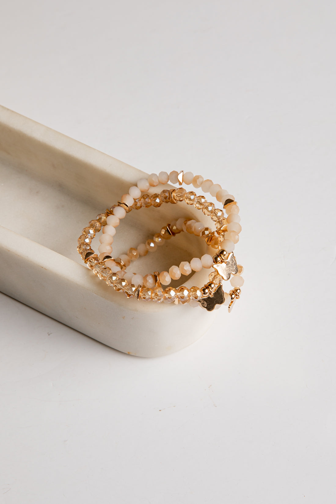 Gold and beige beaded bracelet on a white surface