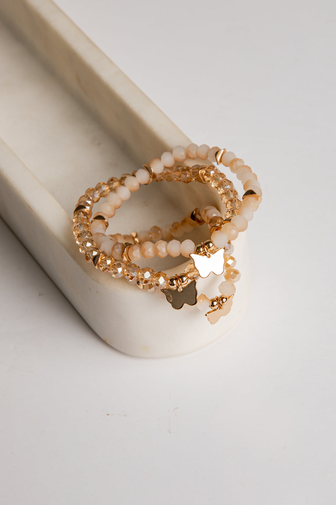 Stack of gold and pearl beaded rings on a white surface