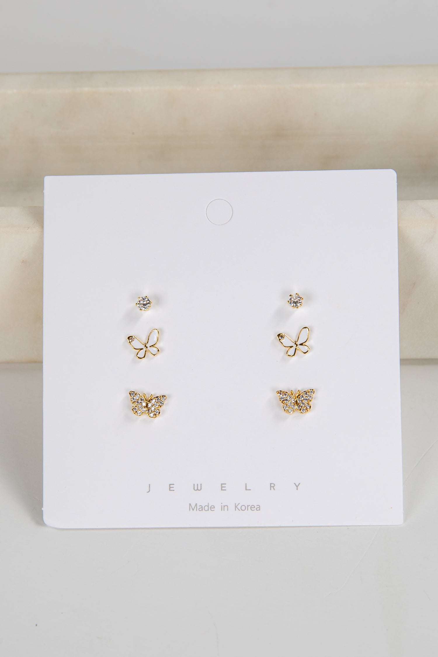 Set of butterfly-shaped earrings on a white card with &