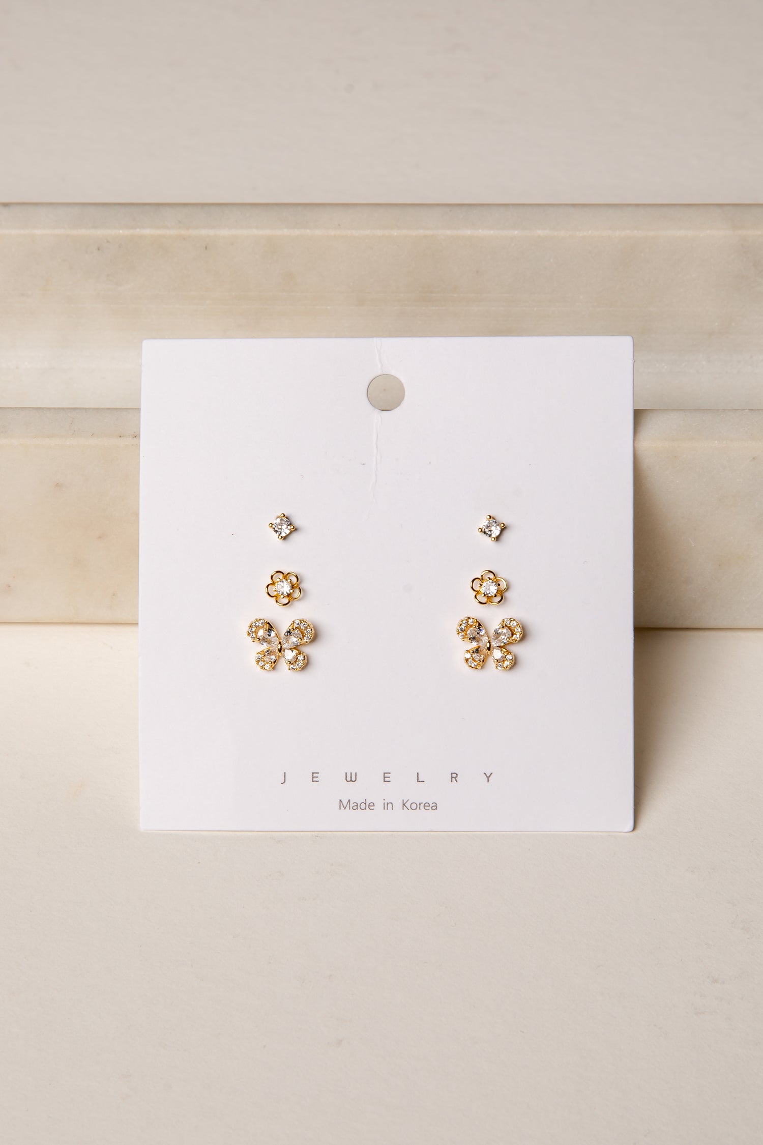 Gold floral earrings on a white card with &
