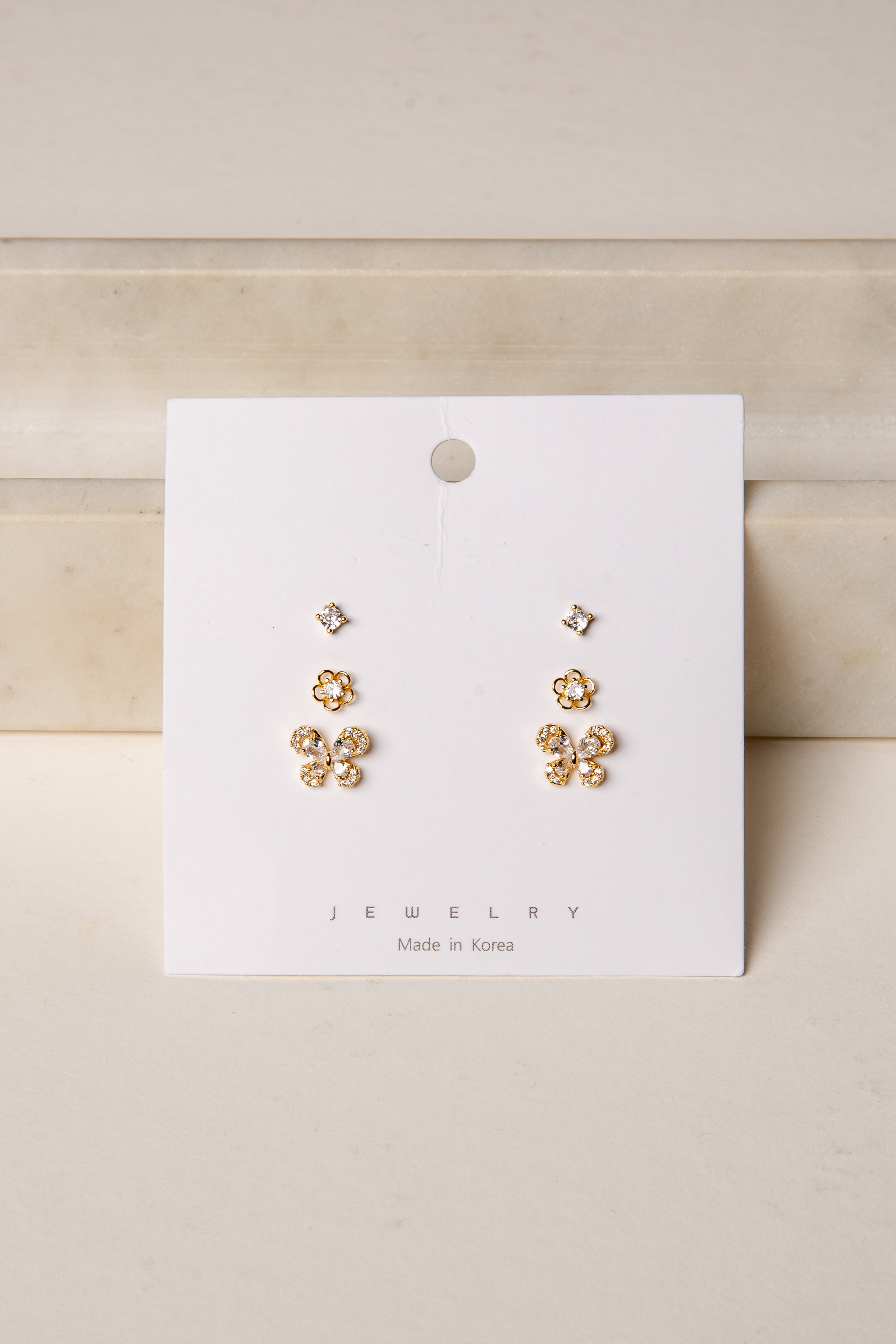 Gold floral earrings on a white card with &