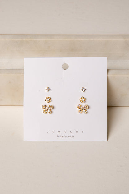Gold floral earrings on a white card with &