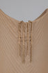 Gold chain earrings on a beige mannequin with a gray background