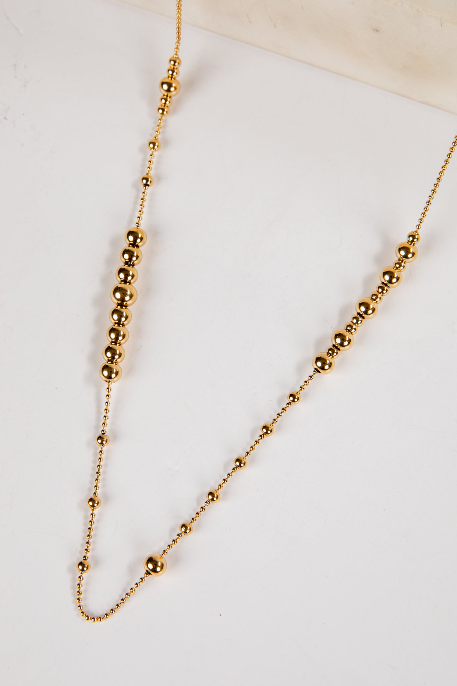 Gold beaded necklace on a white background
