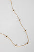 Gold necklace with small square pendants on a light gray background