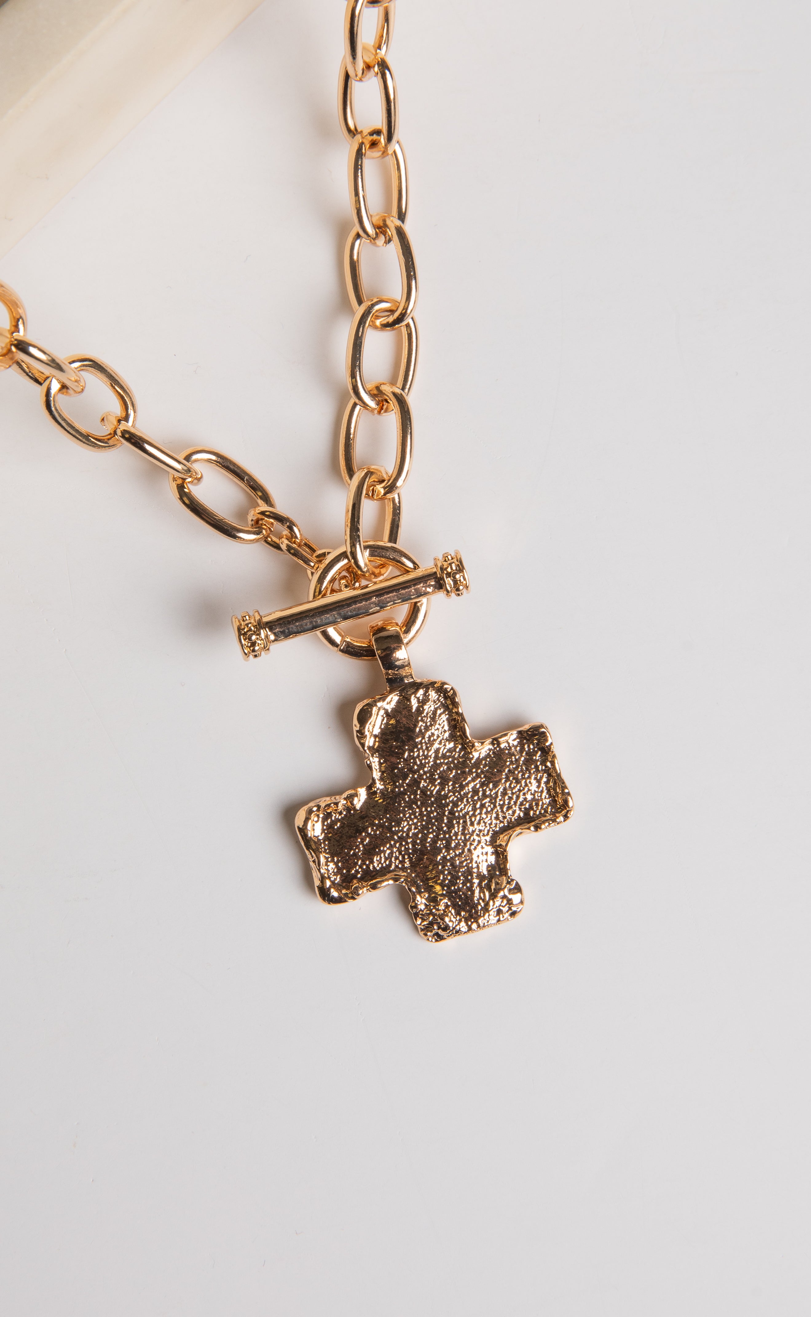 Gold chain necklace with a cross pendant on a white background