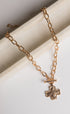 Gold chain necklace with a cross pendant on a white surface