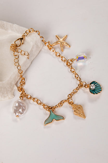 Gold bracelet with various charms including a mermaid tail, starfish, and shell on a light background.