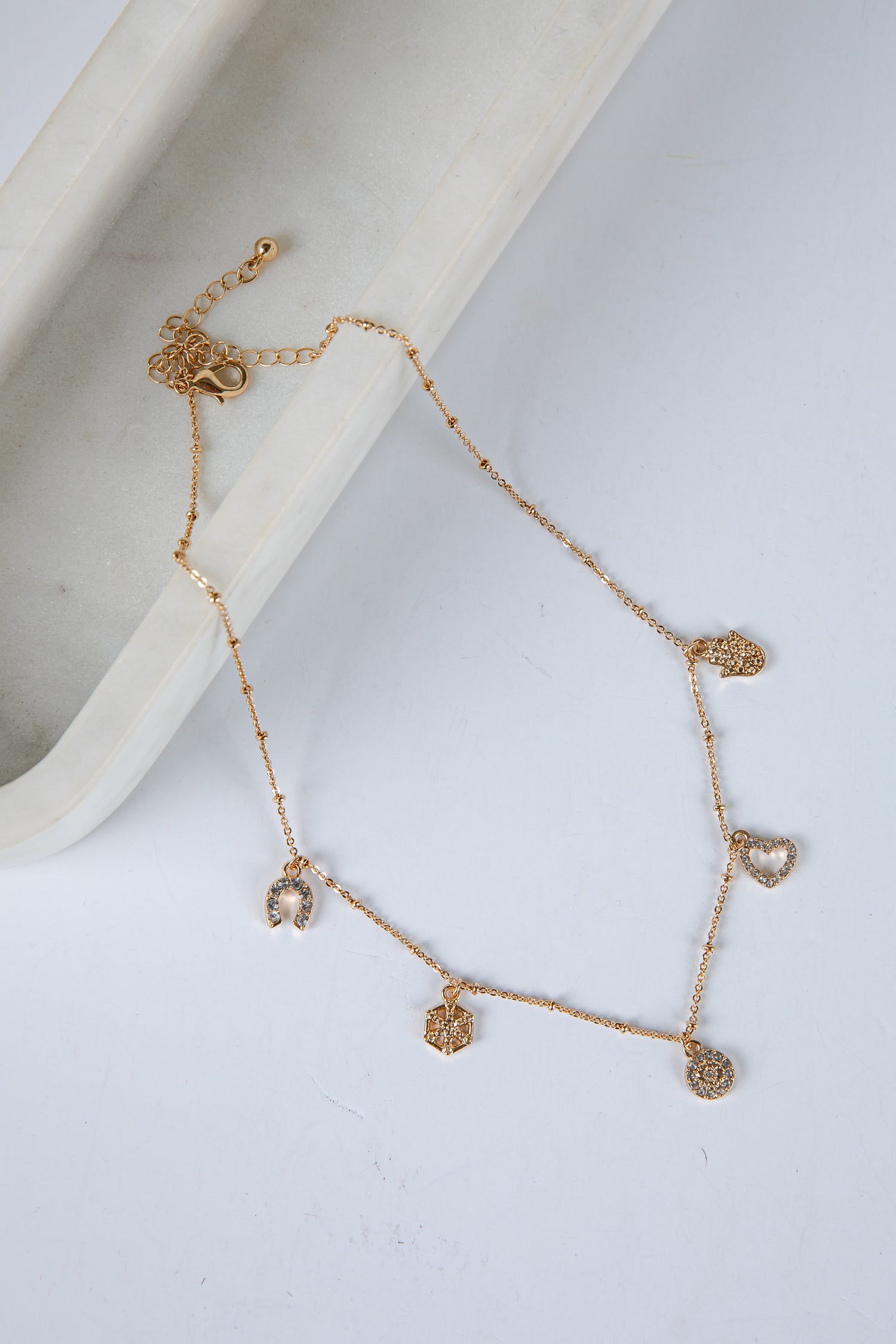 Gold bracelet with heart-shaped charms on a white surface