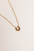 Gold necklace with a sun-shaped pendant on a light beige background