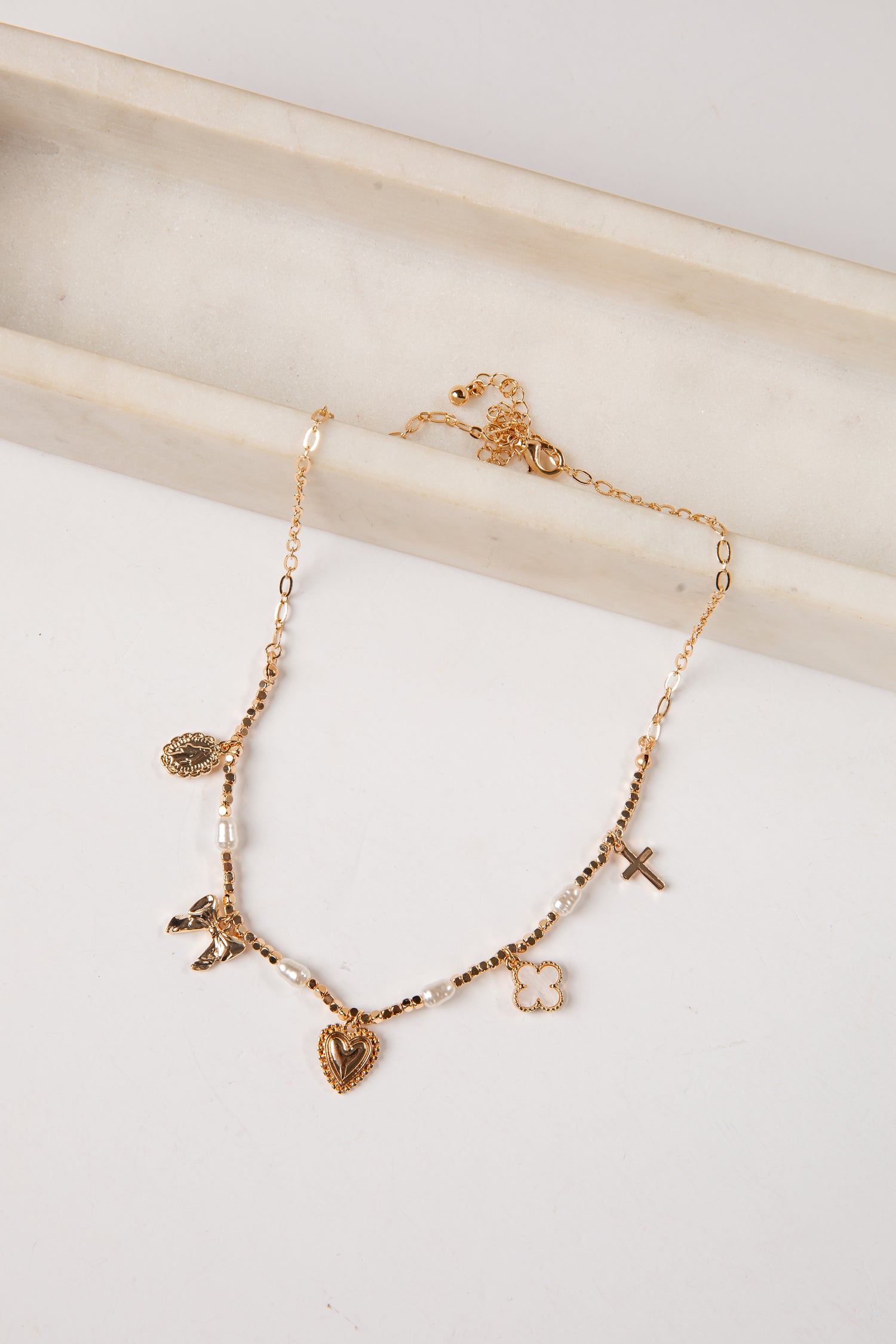 Gold necklace with various charms on a white surface