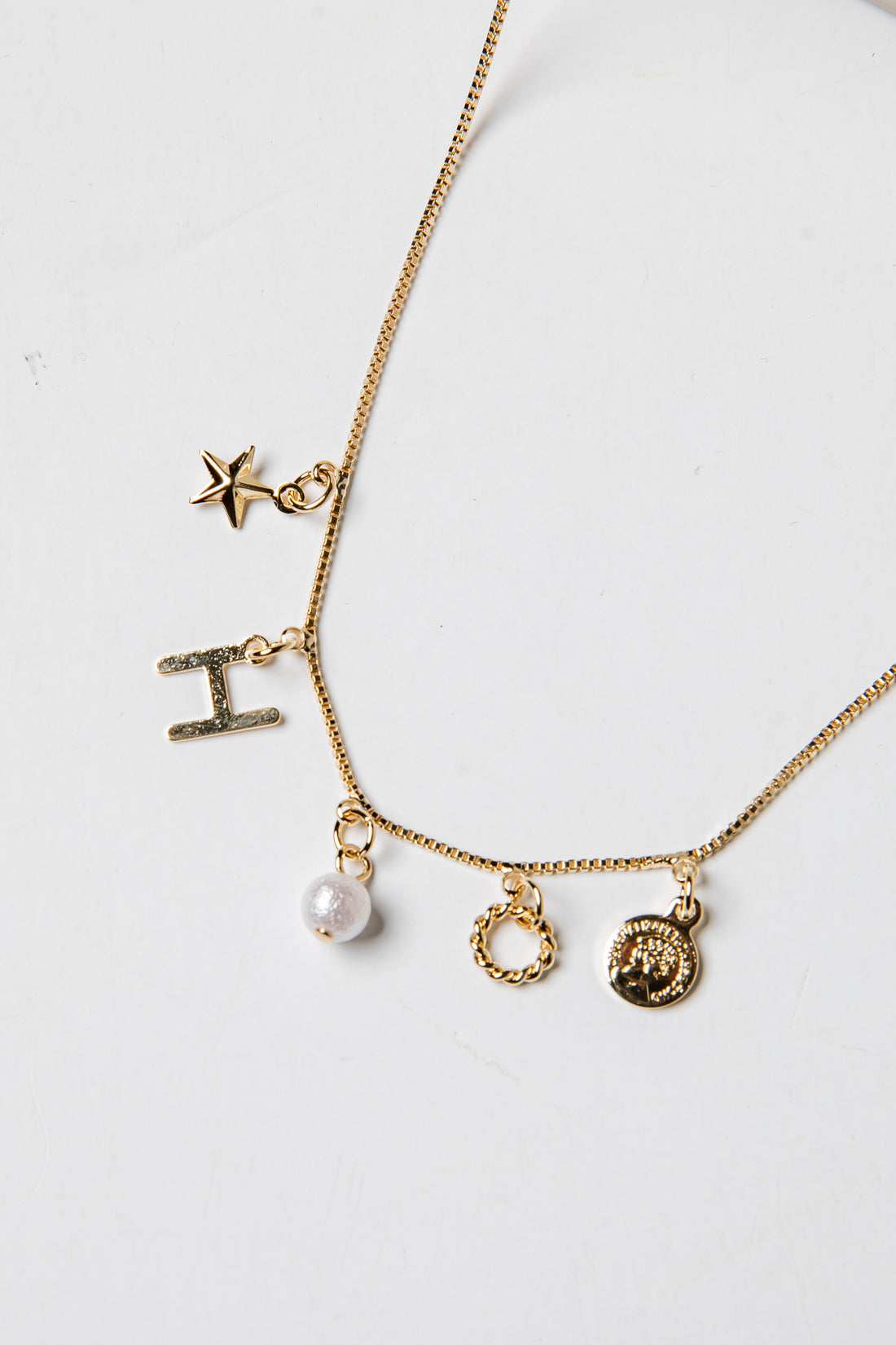 Gold necklace with various charms on a white background