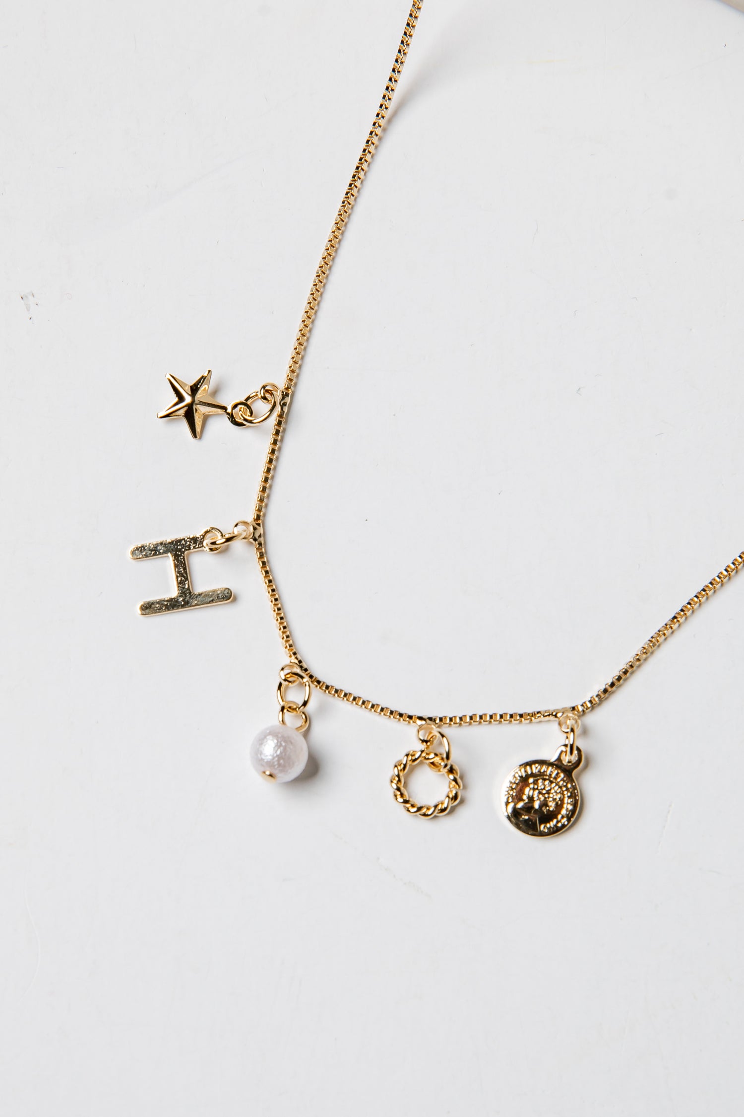Gold necklace with various charms on a white background