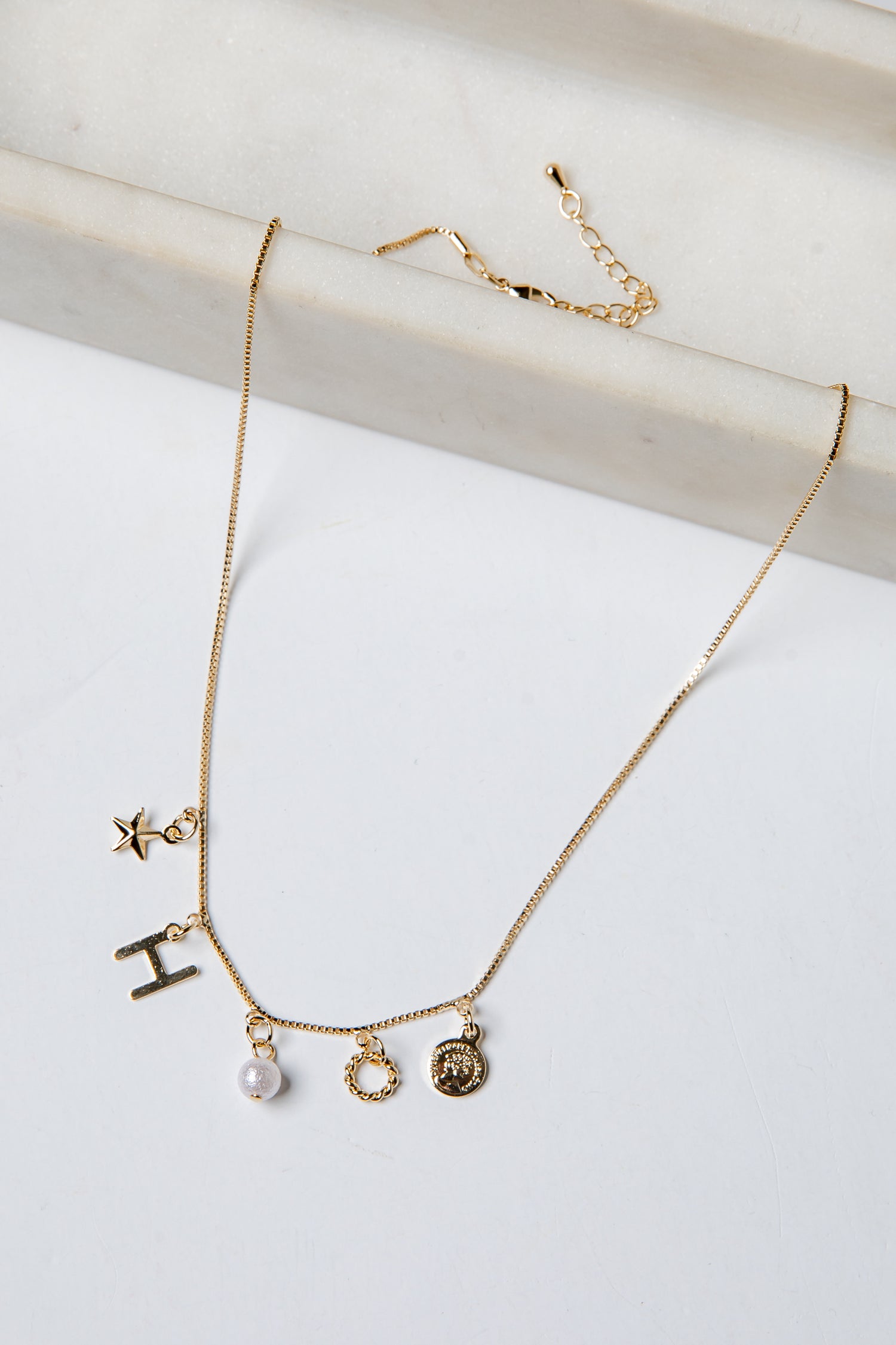 Gold necklace with various charms on a white background