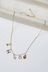 Gold necklace with various charms on a white background