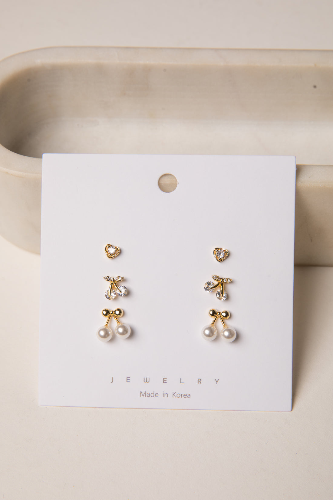 Set of gold earrings on a white card with &
