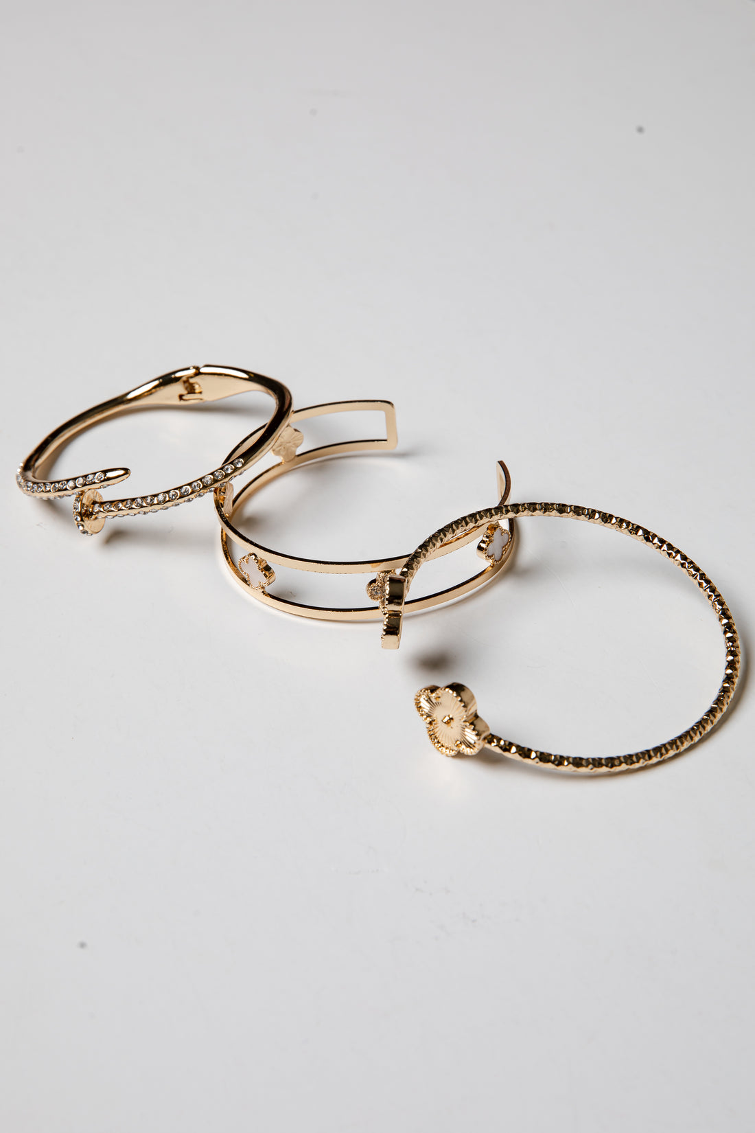 Set of gold bangle bracelets on a light gray background