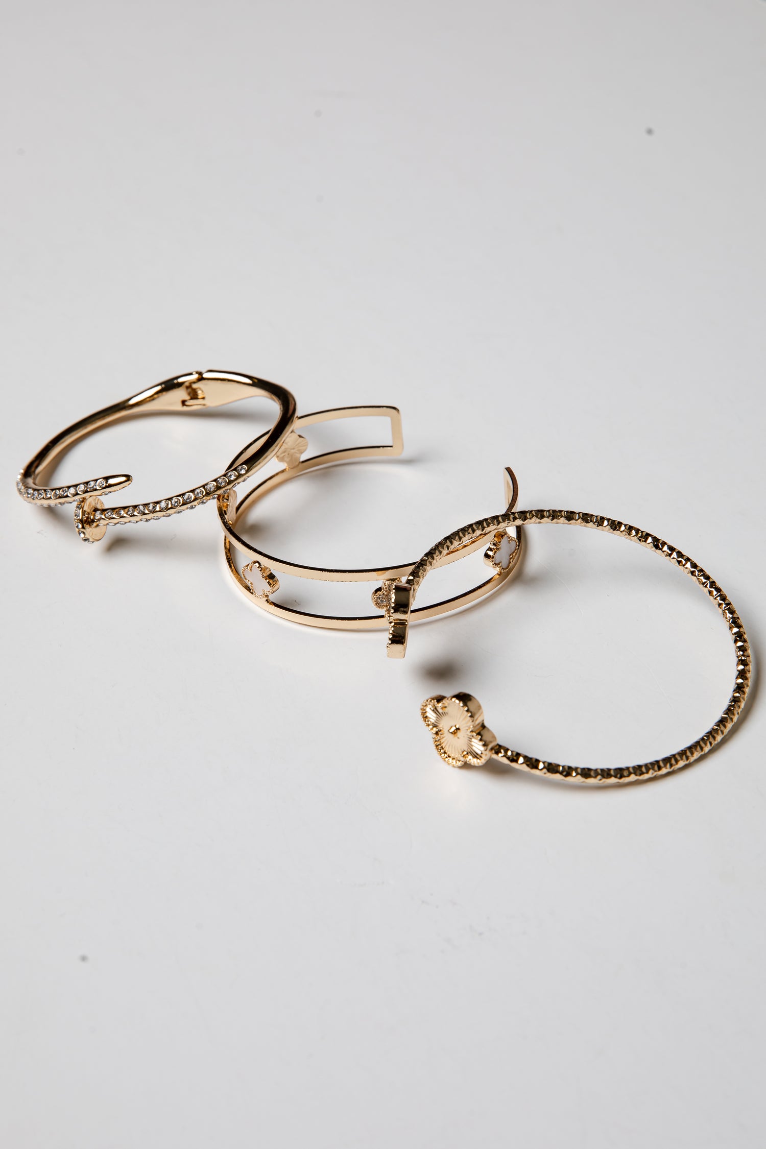 Set of gold bangle bracelets on a light gray background