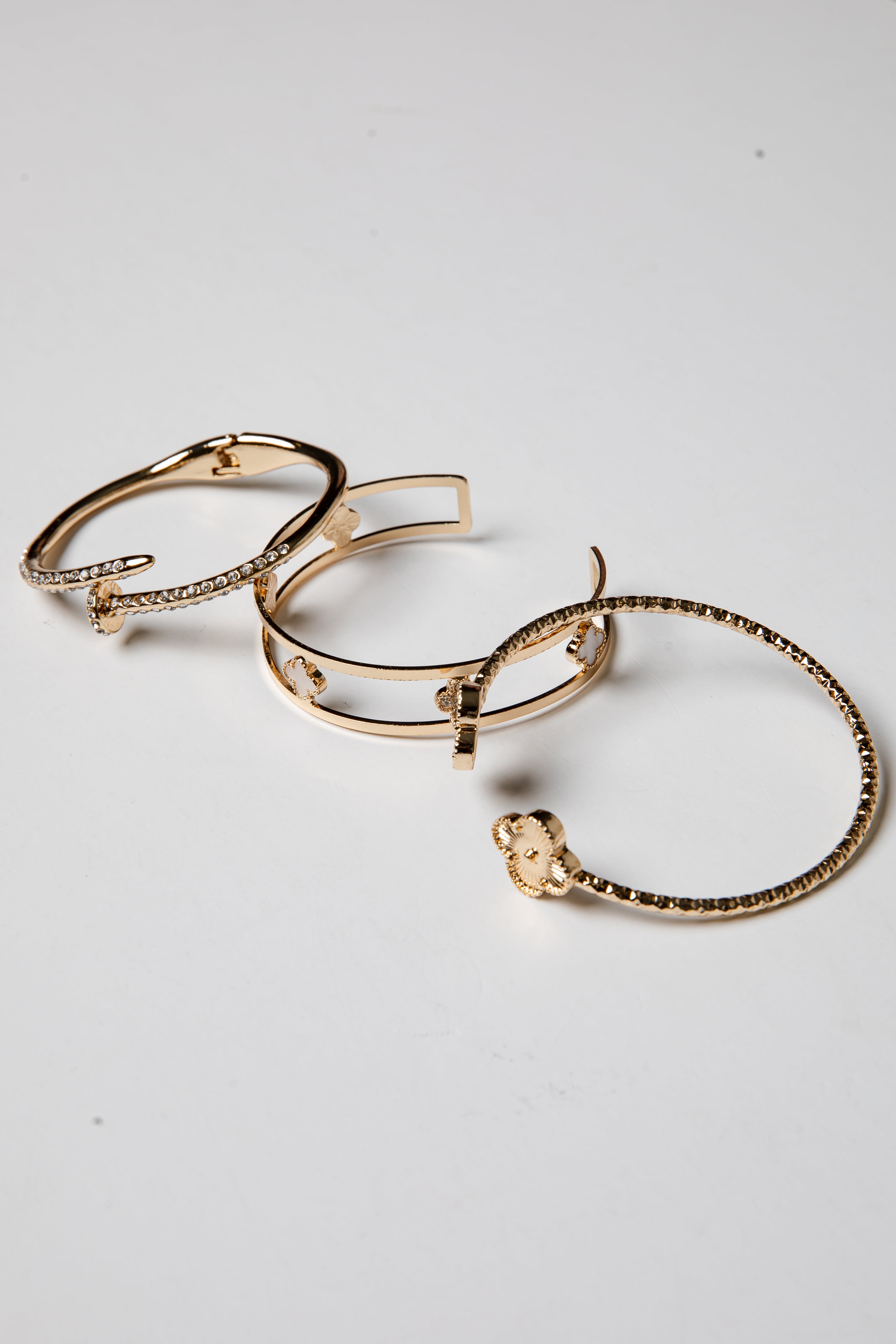 Set of gold bangle bracelets on a light gray background