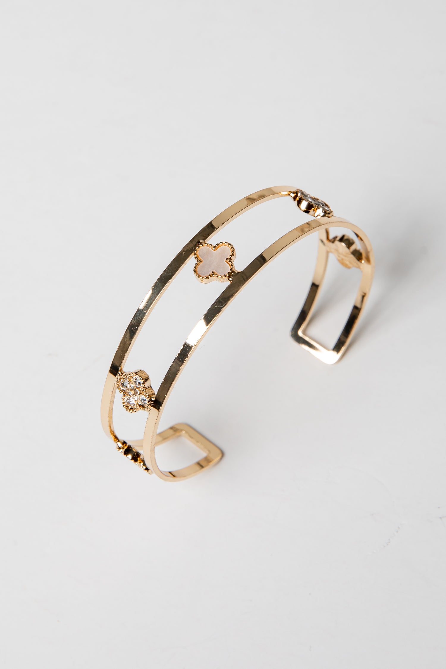 Gold bracelet with decorative elements on a light gray background