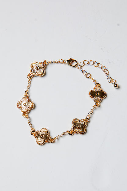 Gold bracelet with floral designs on a light gray background