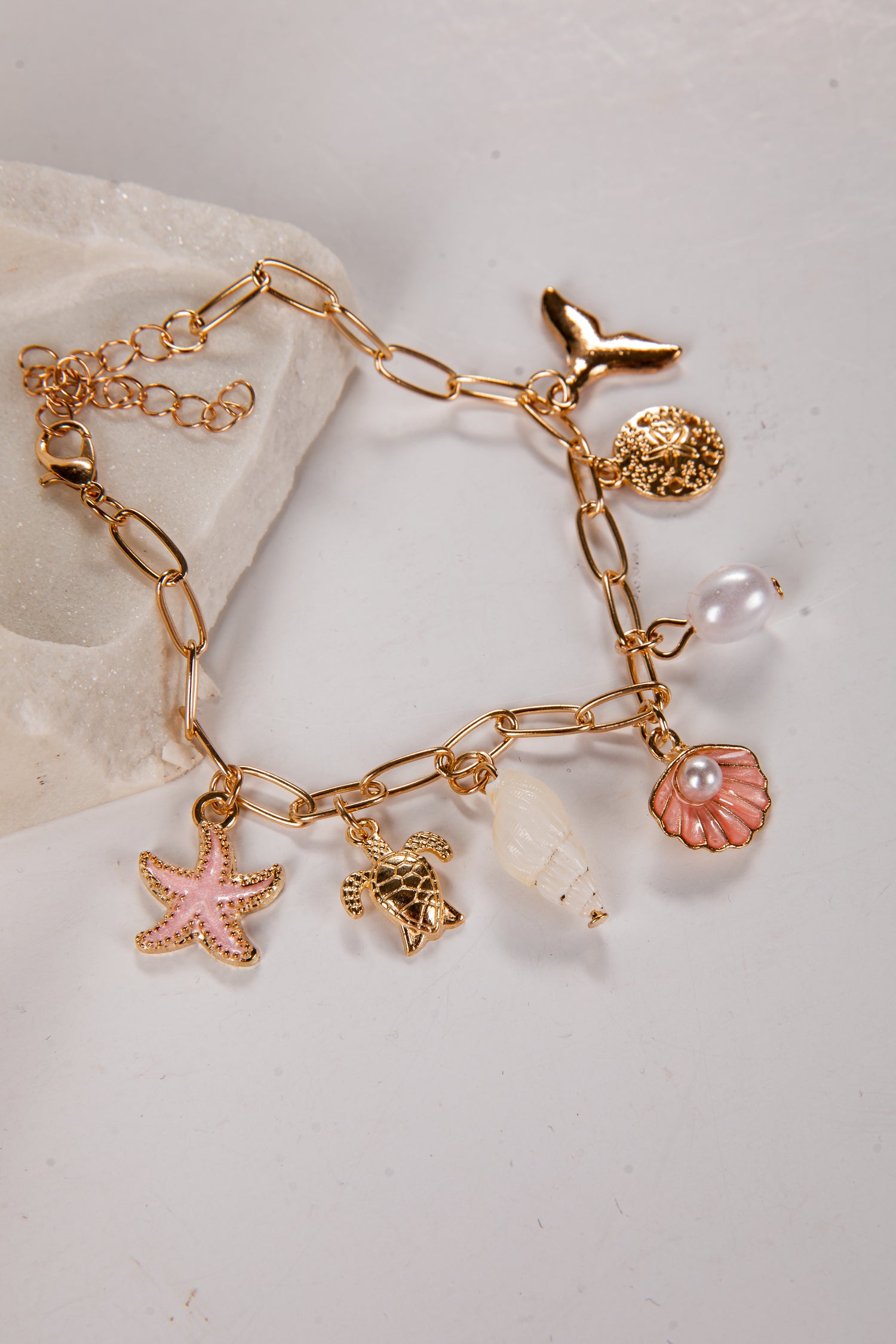Gold bracelet with various charms on a light background