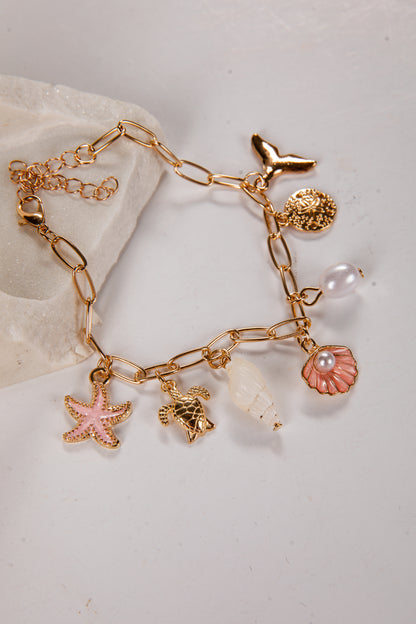 Gold bracelet with various charms on a light background