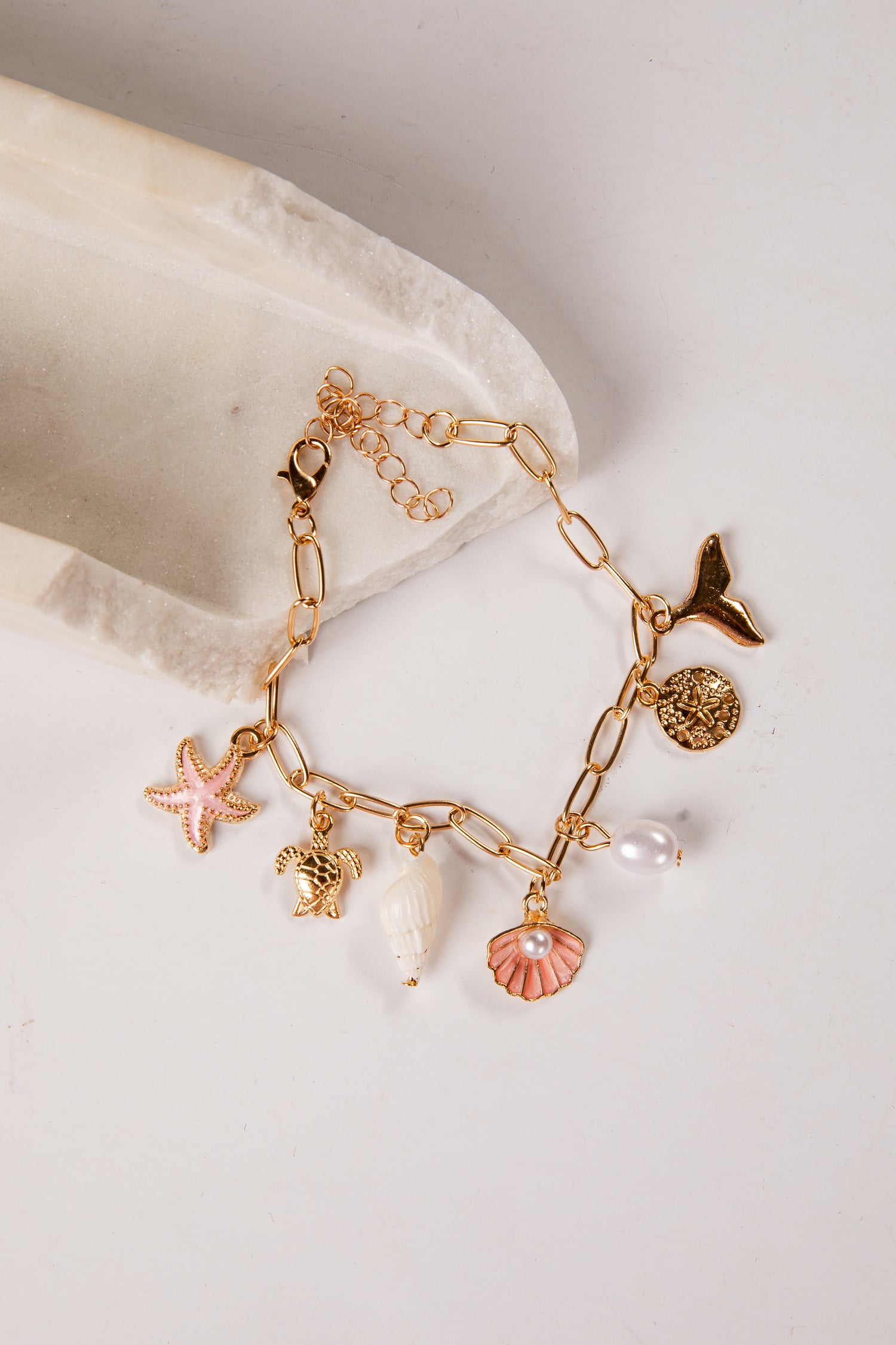 Gold bracelet with various charms on a light background
