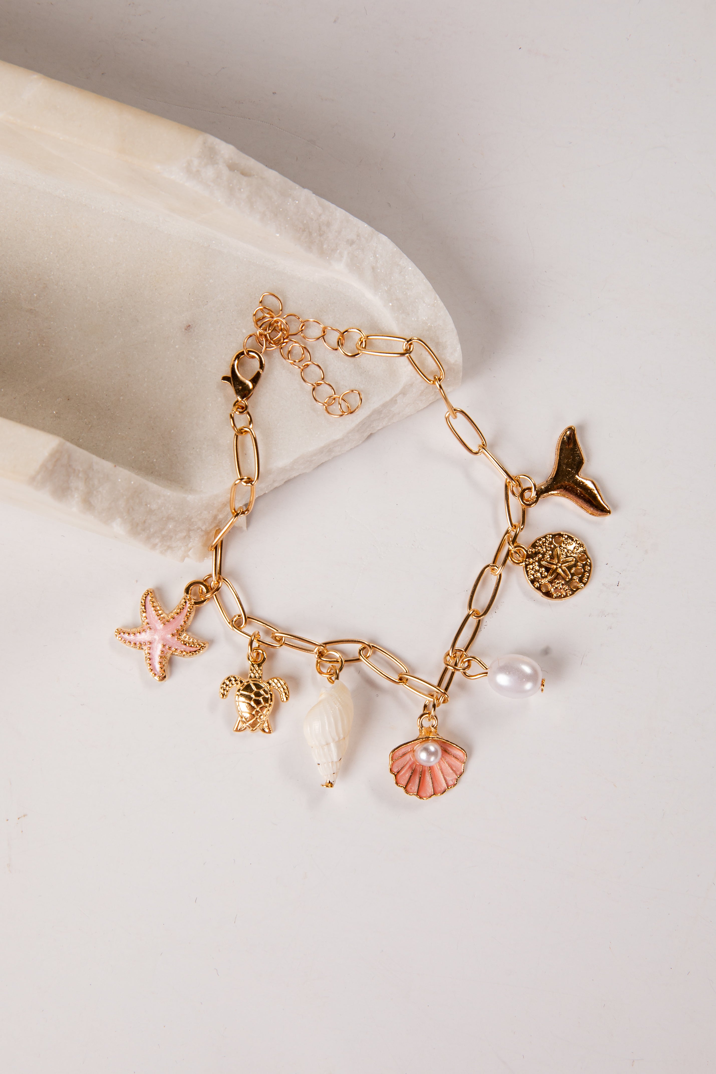 Gold bracelet with various charms on a light background