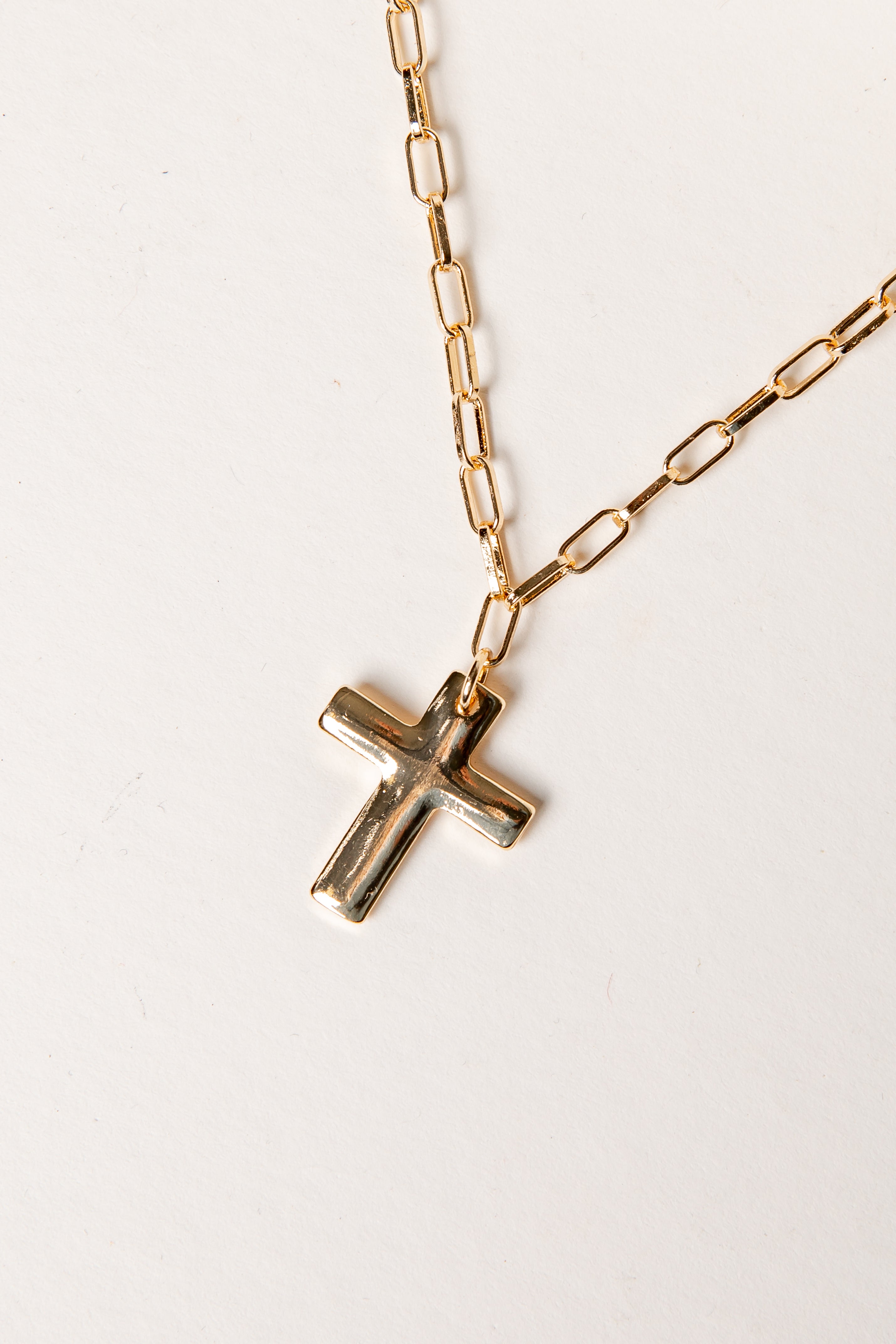 Gold chain necklace with a cross pendant on a white background