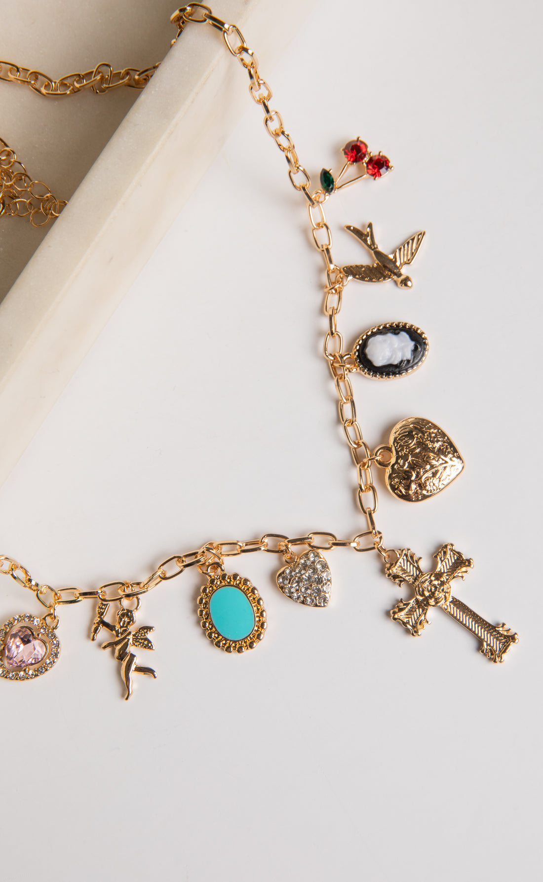 Gold charm bracelet with various charms on a white surface