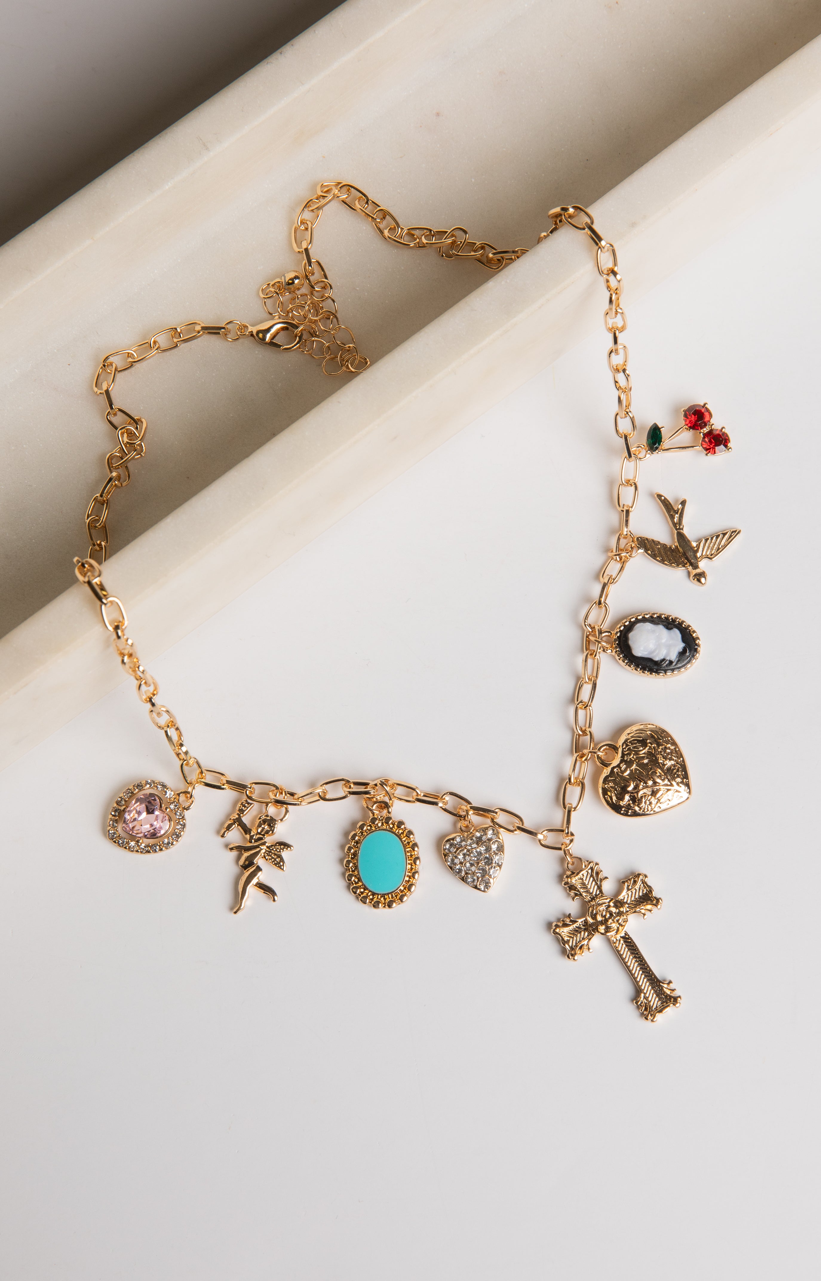 Gold necklace with various charms on a white surface
